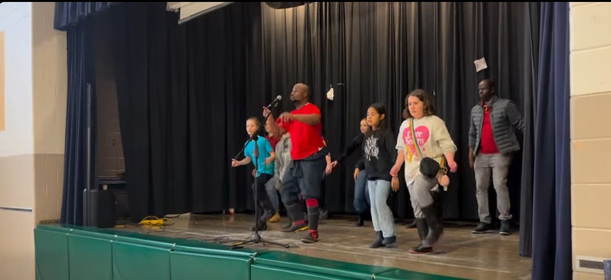 Spectacle Gumboots de Just Asai avec les élèves sur scène, École élémentaire La Mosaïque