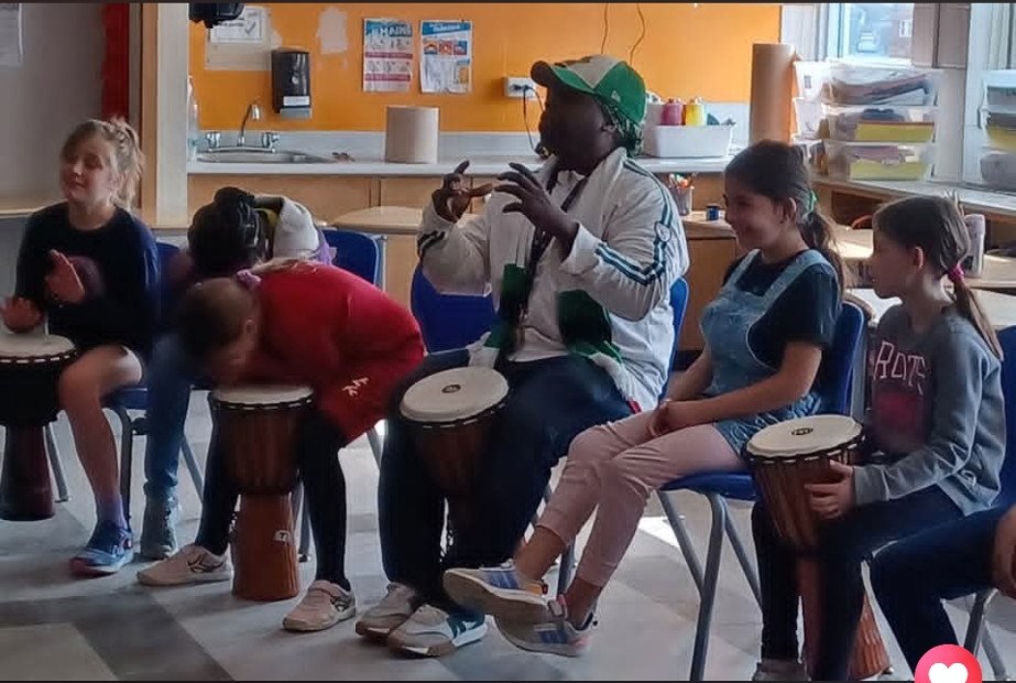 Un musicien anime un atelier de djembé avec les élèves assis en cercle